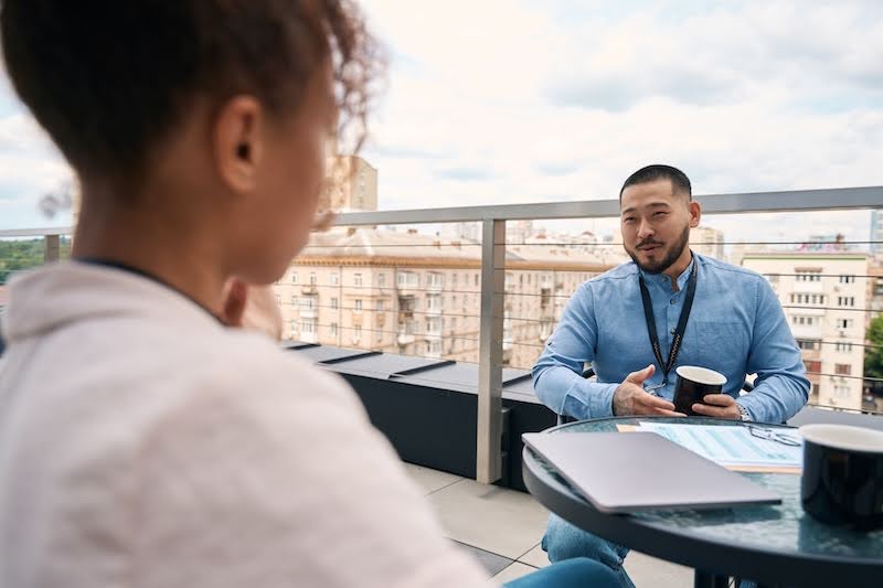 a man is speaking to a woman on a rooftop patio about being a subcontractor