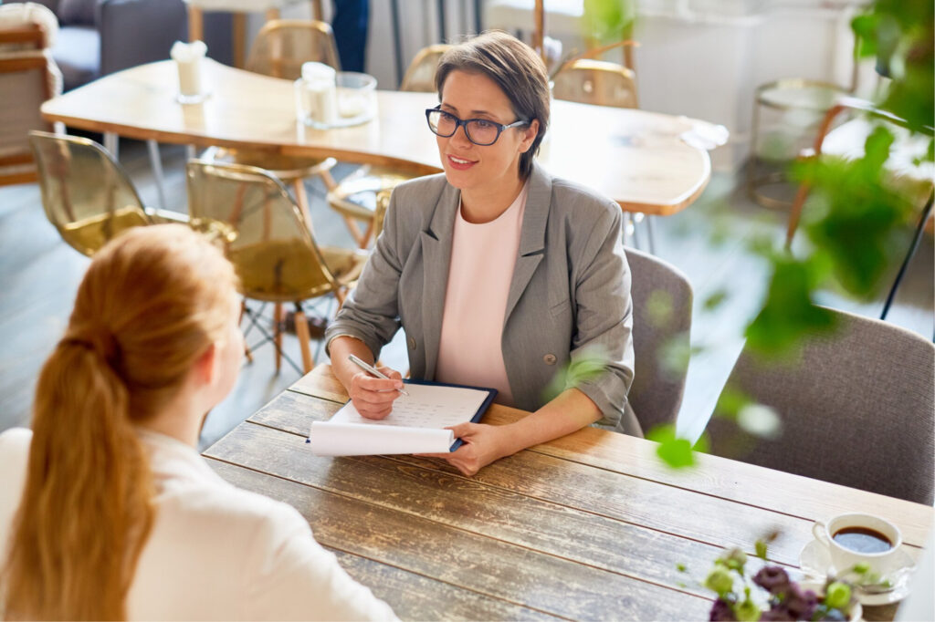 A woman sits with a career coach to discuss how many years of work history should be on a resume.