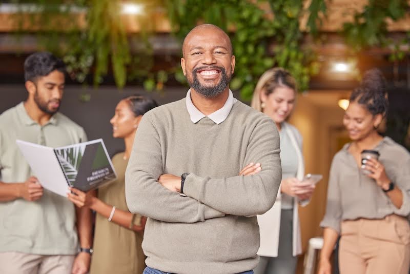 A man smiles and crosses his arms in project management meeting