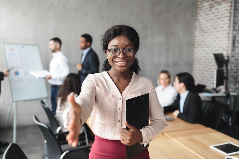 a woman reaches out her hand to accept a temp job in a conference room