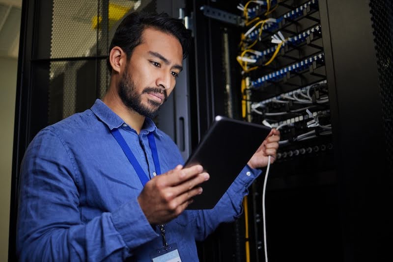 Server room, tablet and engineer with connection cable for maintenance or software update at night