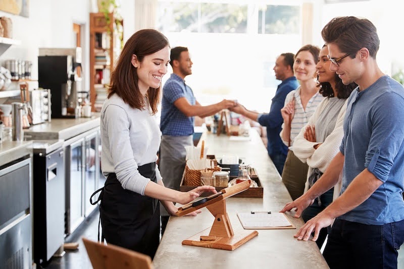 woman checking out a customer at a coffeeshop