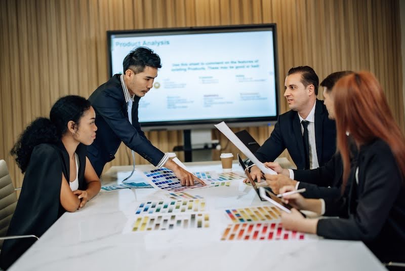 group of business professionals in a conference room looking at color swatches