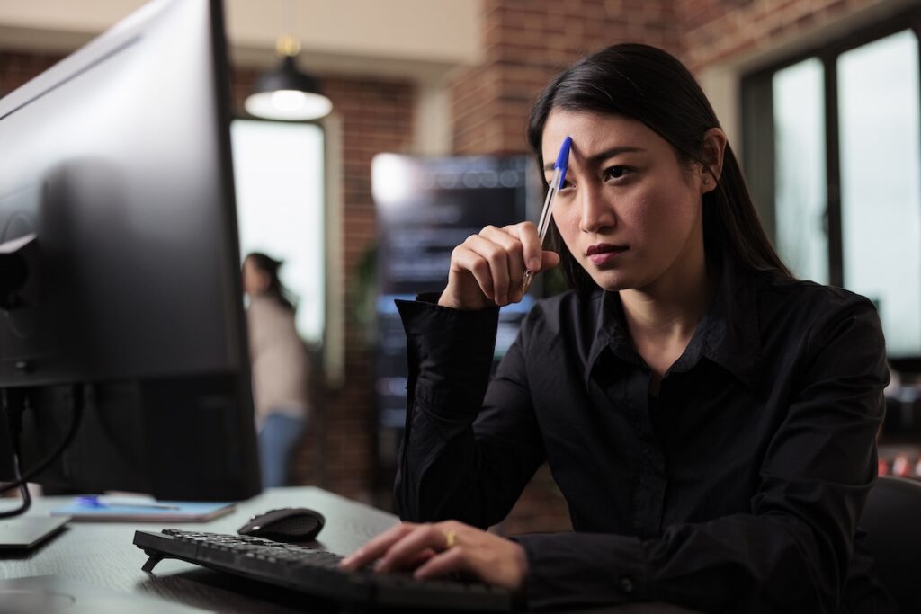 A worker is frustrated at her desk while trying to work up the most mutually beneficial conflict resolution.