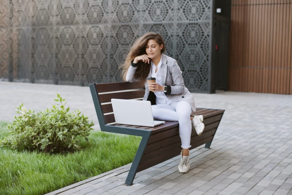 A happy woman sits outdoors as she pauses to reflect on a situation to present the best conflict resolution.